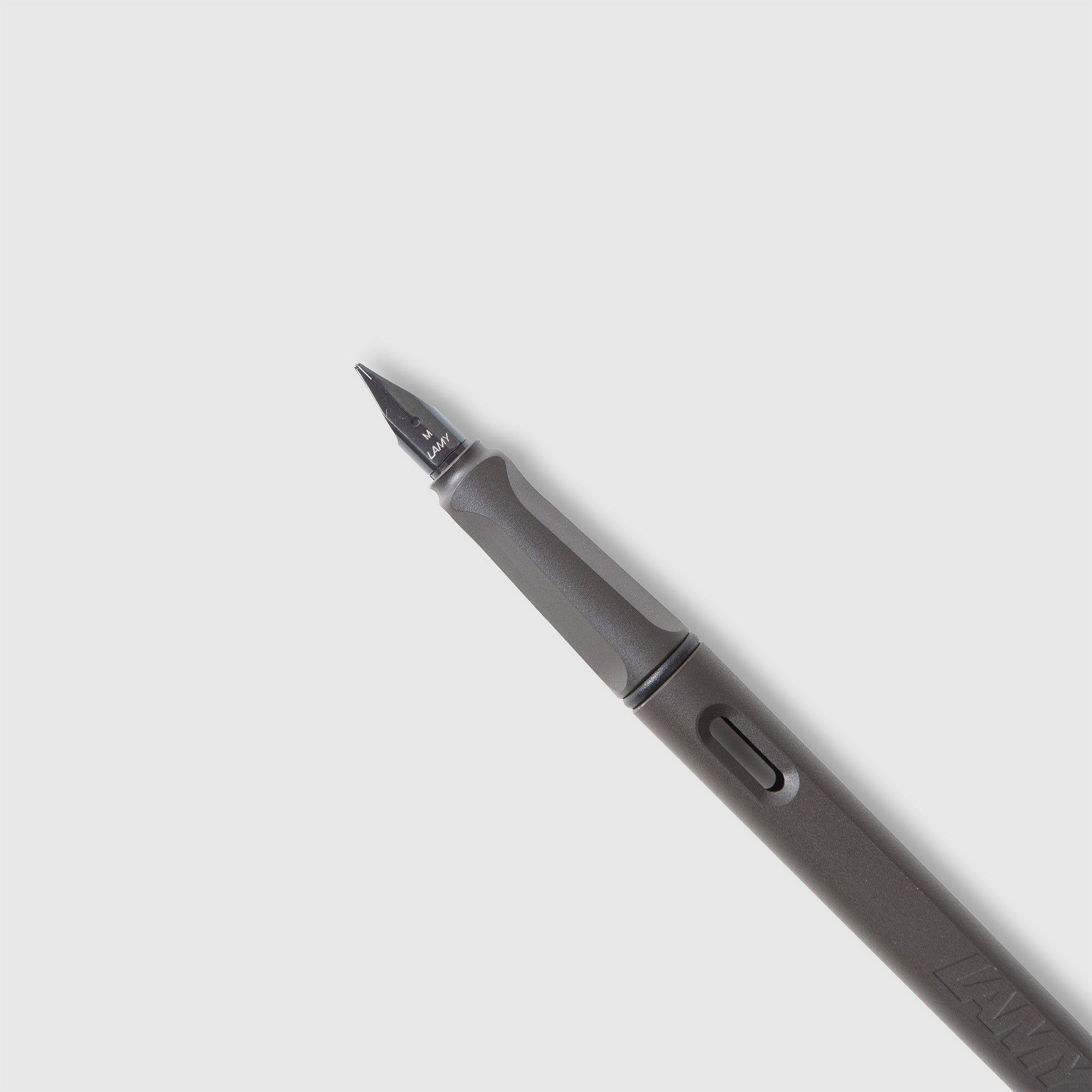Ein schwarzer LAMY safari Füllhalter von Lamy mit spitzer Edelstahlfeder liegt diagonal auf einer schlichten hellgrauen Oberfläche. Der matte Korpus verfügt über einen Top-Clip, der sein modernes Design unterstreicht.