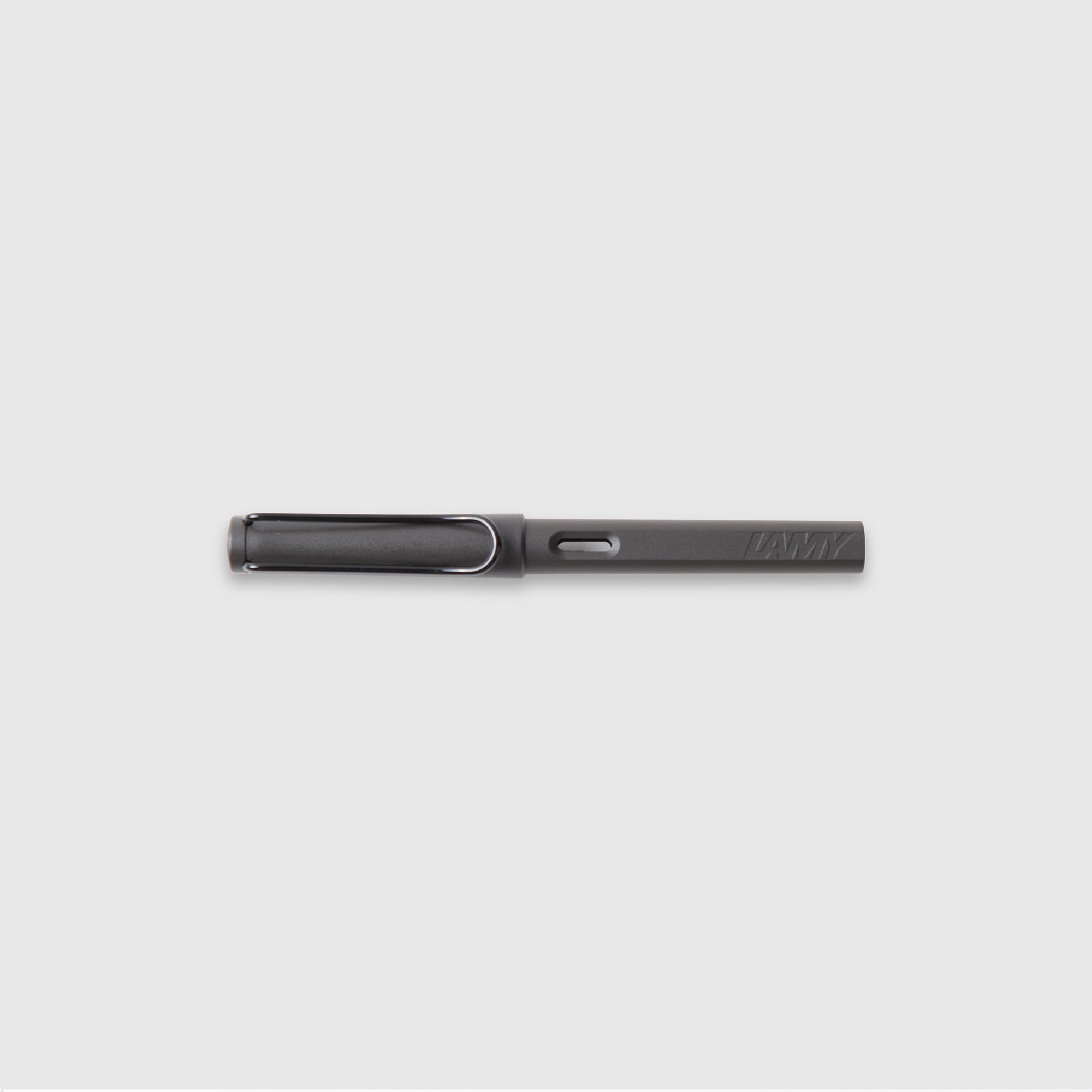 Der LAMY safari Tintenpatronenroller - roll-ink von Lamy ist ein eleganter, mattschwarzer Tintenroller mit Kappenclip, der horizontal auf einem hellgrauen Hintergrund abgebildet ist. Sein ergonomischer Griff sorgt für Komfort und den typischen minimalistischen Stil bei jedem Strich.