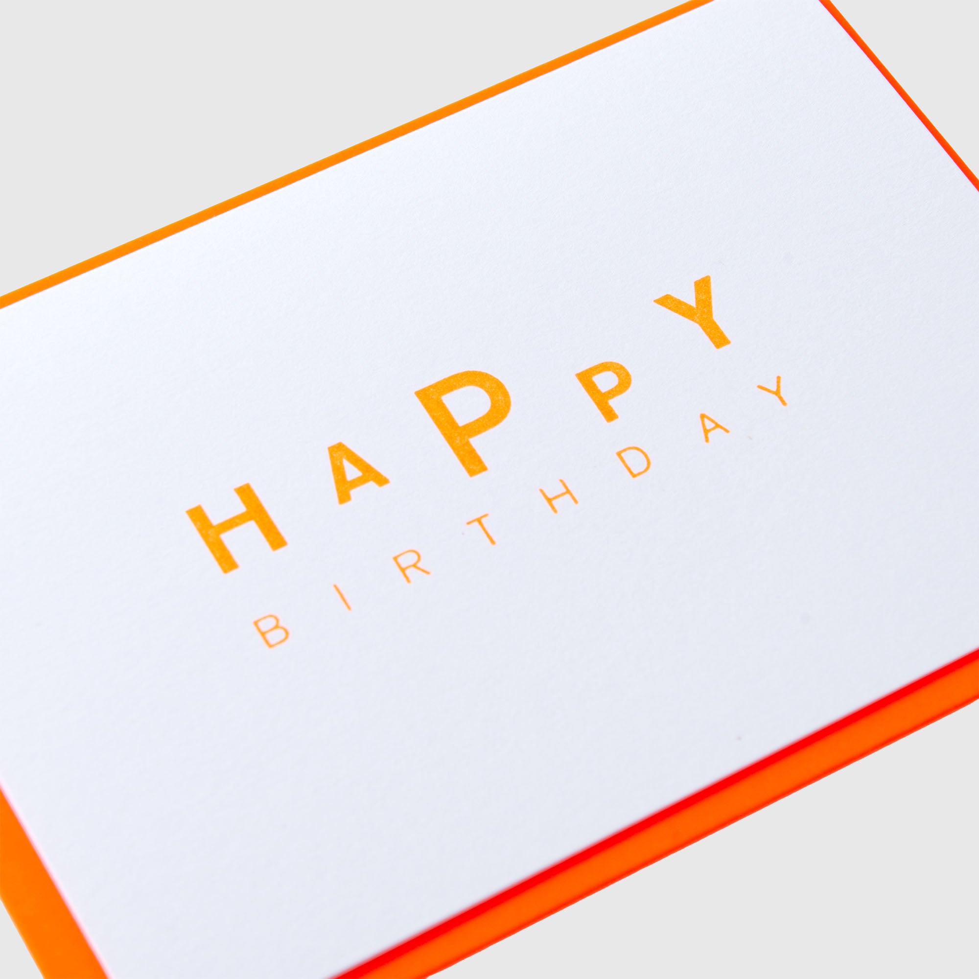 Die „Dancing Birthday – Karte  Kuvert“ von Le Typographe ist eine weiße Geburtstagskarte mit orangefarbenen Rändern, auf der der Schriftzug „HAPPY BIRTHDAY“ in minimalistischen orangefarbenen Großbuchstaben auf hellgrauem Hintergrund zu sehen ist. Ein eleganter Letterpress-Druck unterstreicht das Design, und die Karte wird mit einem auffälligen neonorangefarbenen Umschlag geliefert, der für eine moderne und festliche Note sorgt.