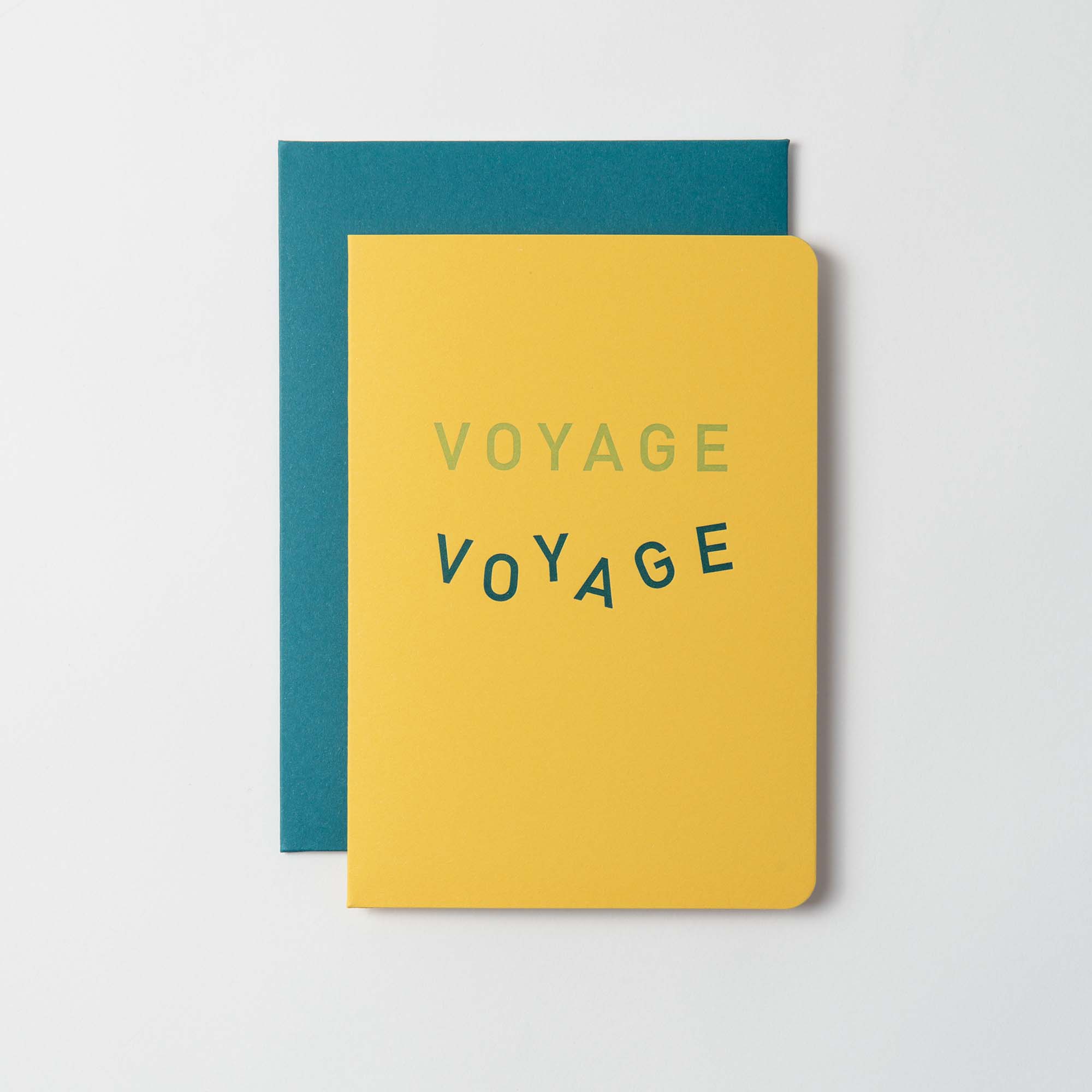 Die Voyage Voyage Karte und Kuvert von Le Typographe besteht aus gelben Karten, auf denen zweimal "VOYAGE" in unterschiedlichen Schrifttypen auf tealfarbenem Hintergrund steht, was an französische Motive und klassische Letterpress-Karten auf weißem Hintergrund erinnert.