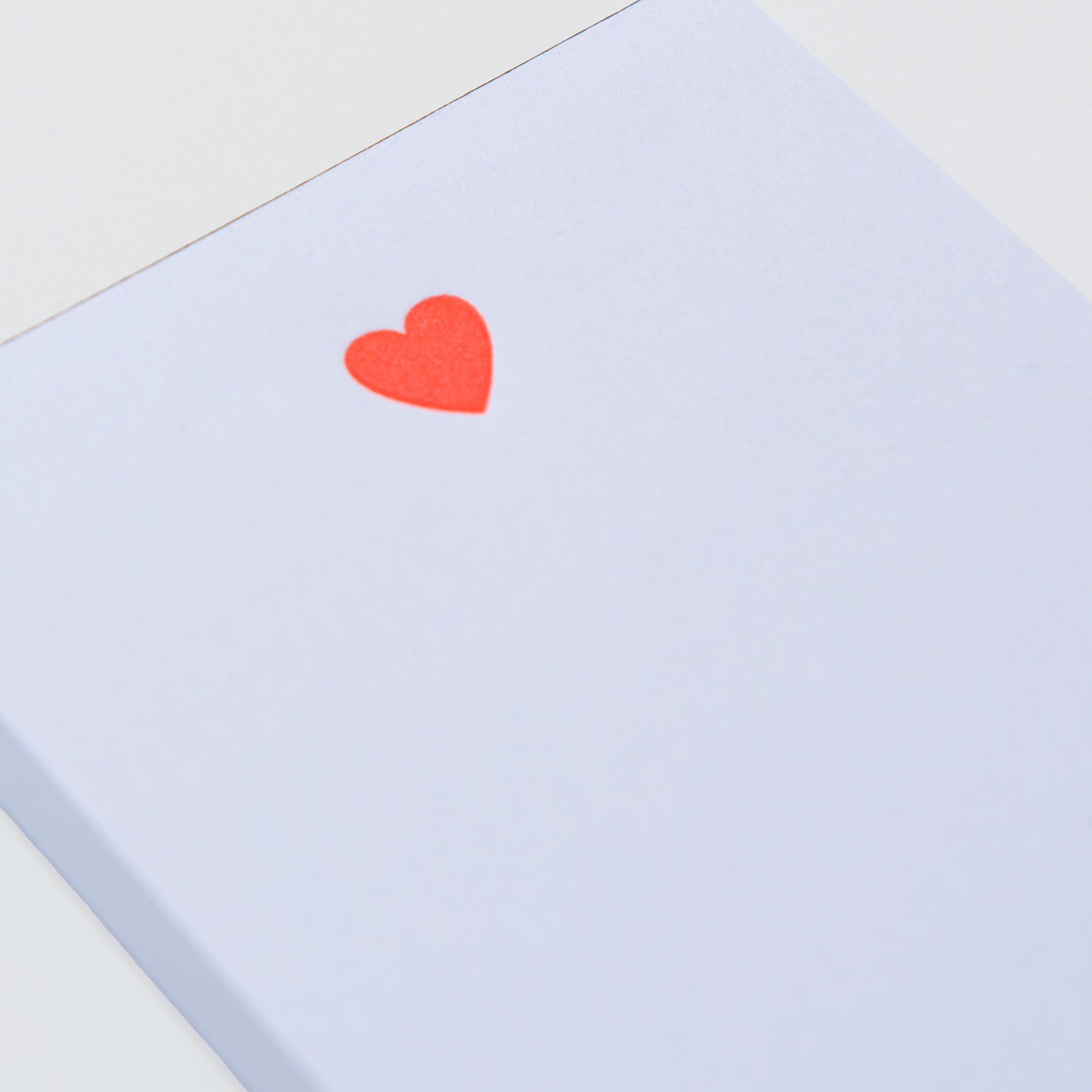 Ein weißer Notizblock mit einem kleinen roten Herz in der oberen linken Ecke und Mini-Abreiss-Seiten zum einfachen Heraustrennen aus der Mini-Notizblöcke-Kollektion „Kiss Kiss, Love Love“ von Le Typographe.