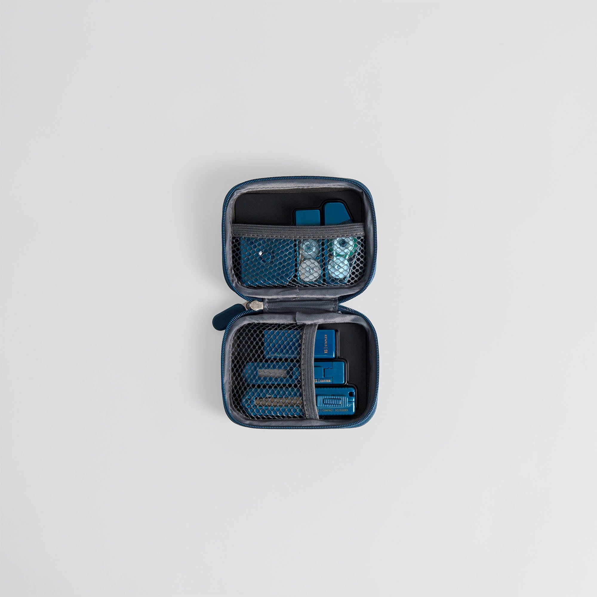 Das Midori XS Stationery Kit von Midori ist ein kompaktes, quadratisches Etui mit Reißverschluss und Netztaschen, das für verschiedene kleine Schreibwaren geeignet ist. Es ist auf einem hellgrauen Hintergrund abgebildet.