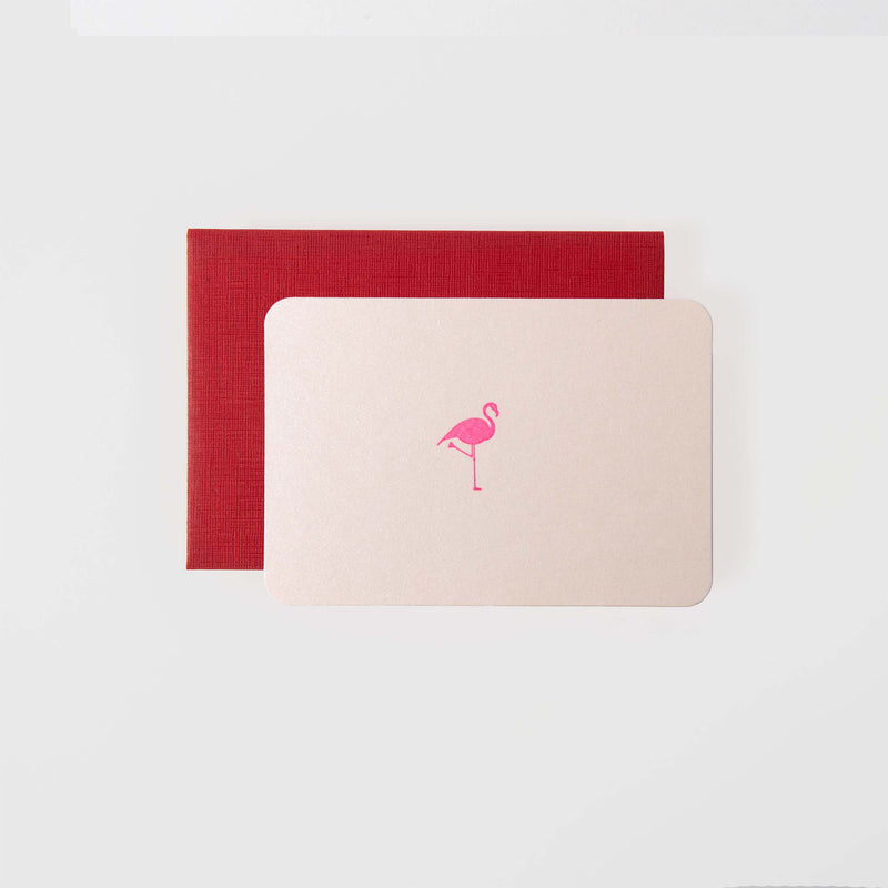 Die Flamingo - Mini Karte von Le Typographe zeigt einen kleinen rosa Flamingo mit exquisiten Letterpress-Details, der auf einem schlichten roten Umschlag auf weißem Hintergrund ruht. Sein schlichtes Design bildet einen schönen Kontrast zum auffälligen Umschlag und unterstreicht die Eleganz der Karten-Handwerkskunst.