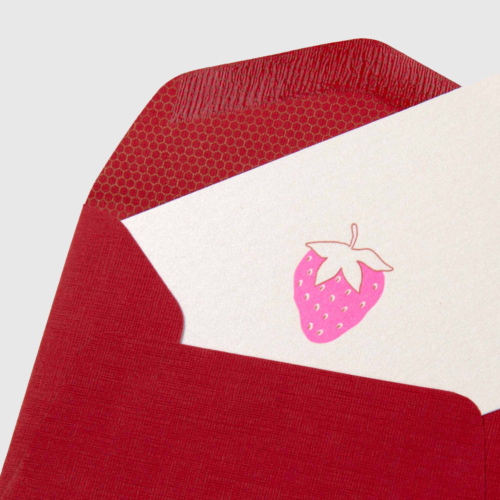 Ein roter, strukturierter Umschlag von Le Typographe aus der Serie „Erdbeere – Mini Karte“ mit einer weißen Karte, auf der in der Mitte eine minimalistische rosa Erdbeer-Illustration zu sehen ist. Der Umschlag ist innen mit einem sechseckigen Muster ausgekleidet, das die meisterhafte Buchdruckkunst zur Geltung bringt.