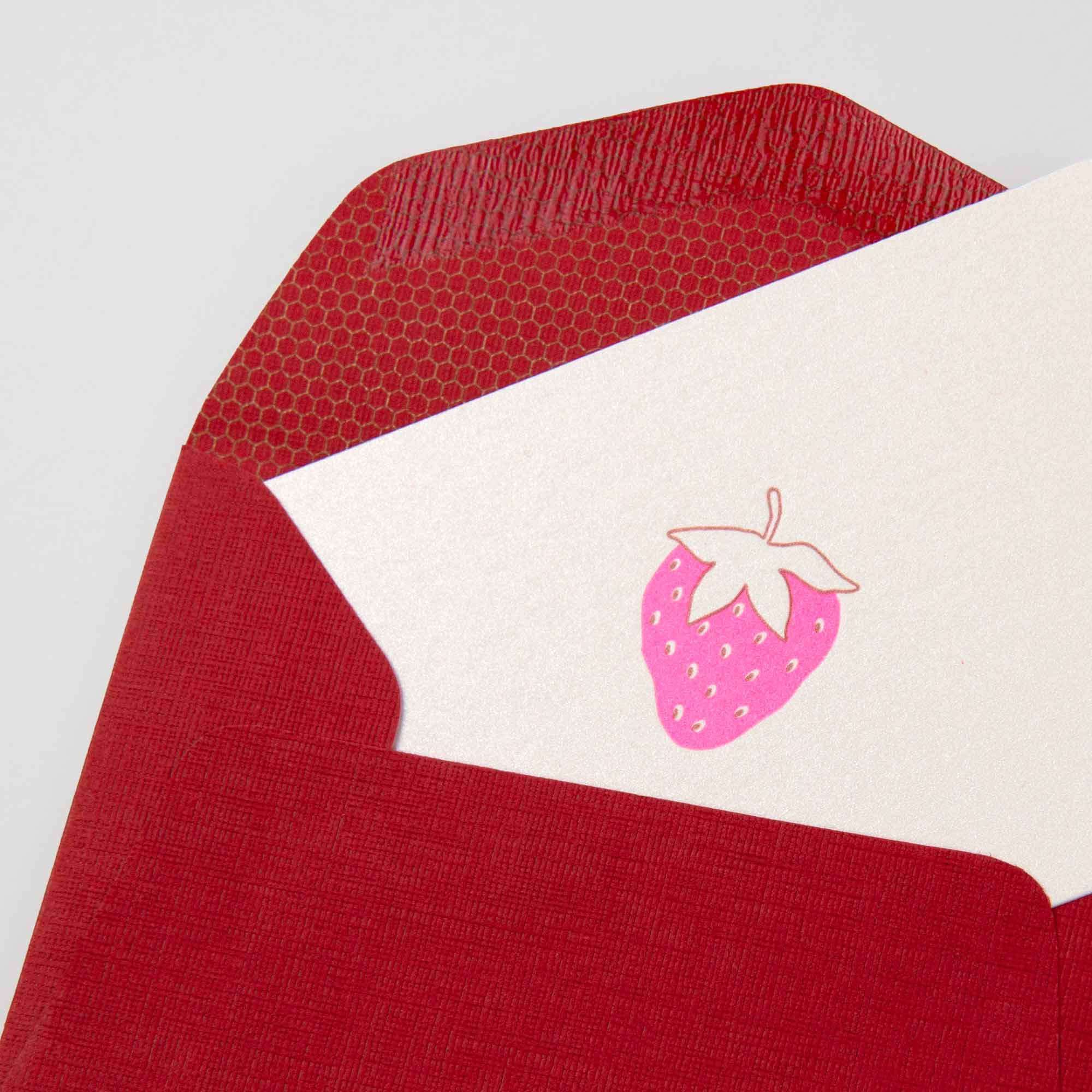 Die Erdbeere - Mini Karte von Le Typographe zeigt eine rosafarbene Erdbeer-Illustration auf weißem Karton, die teilweise in einen strukturierten roten Umschlag mit gemustertem Innenfutter geschoben wird und die Essenz der belgischen Sommersüße einfängt.