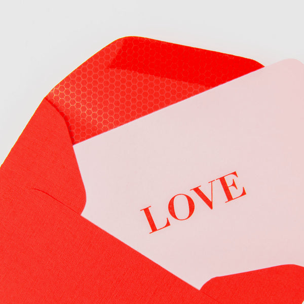 Ein teilweise geöffneter roter Le Typographe-Umschlag offenbart eine weiße „LOVE“-Karte, die mit Buchdruckpräzision gefertigt wurde. Im Inneren ergänzt das glänzende sechseckige Muster ein elegantes rot-weißes Farbschema und zeigt die exquisite Kunstfertigkeit von Karten in ihrer LOVE - Mini-Karte.