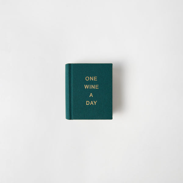 Ein kleines Buch von paperlux.store mit dem Titel „One Wine a Day“ hat einen flaschengrünen Einband mit goldener Schrift und wird auf einem schlichten weißen Hintergrund angezeigt.