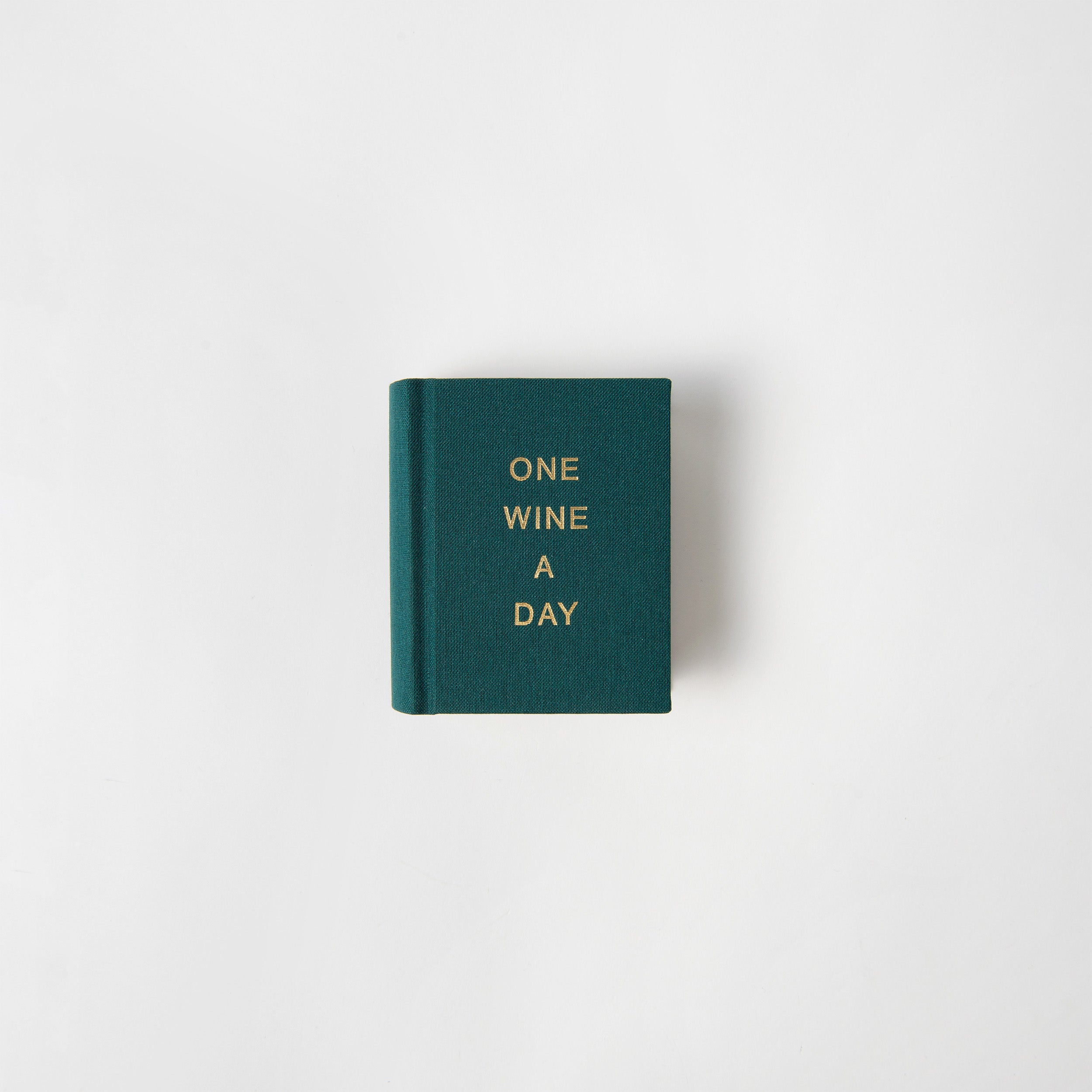 Ein kleines grünes Buch, One Wine a Day von paperlux, mit goldenem Einband und weißem Hintergrund - ein perfekter Sommelier-Begleiter und ein Wein-Tagebuch, liebevoll hergestellt in Hamburg.