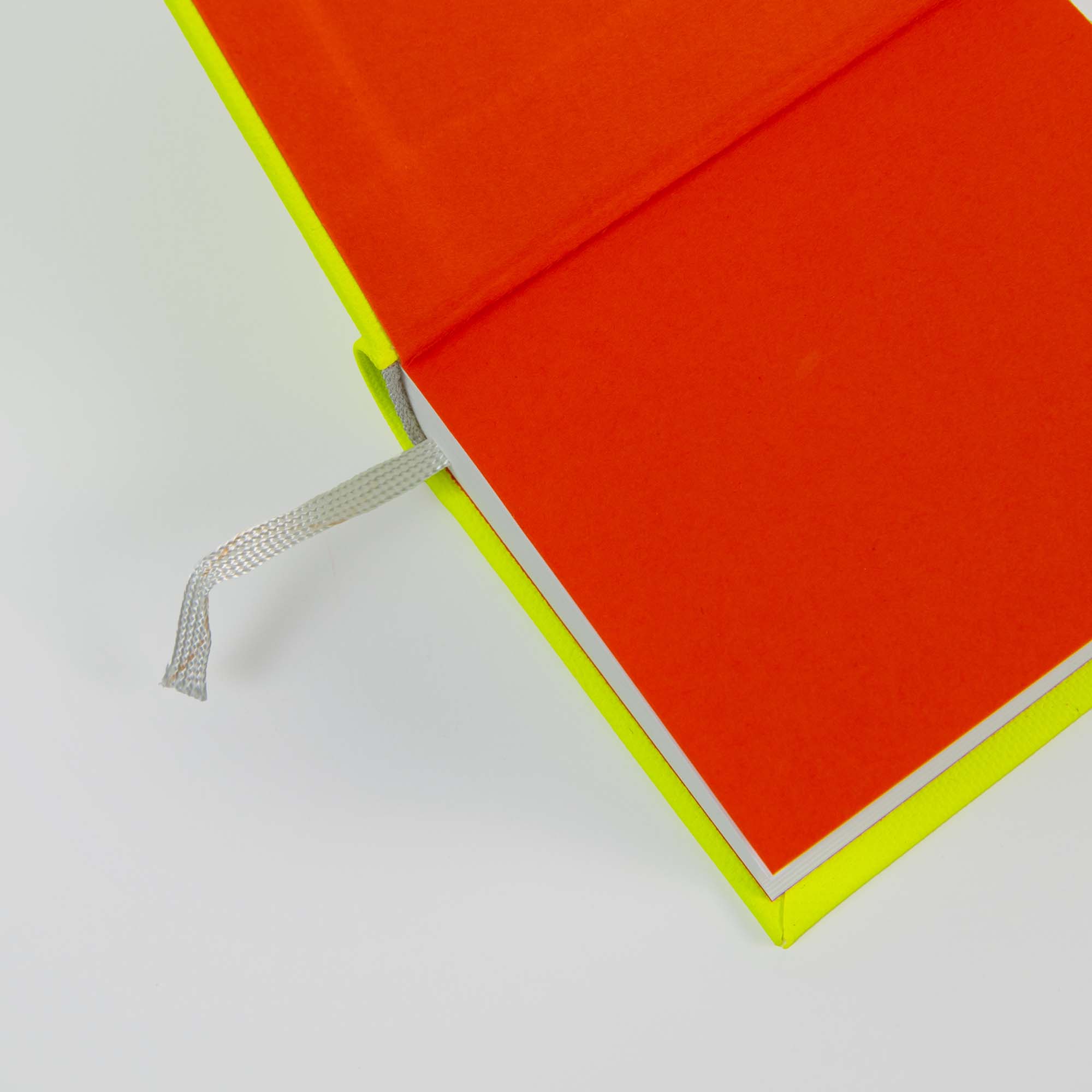 Das OWAD Neon-Notizbuch von paperlux hat leuchtend orangefarbene Seiten, einen gelben Einband und ein Lesezeichen mit silbernem Band - ideal für Tagebucheinträge oder als einzigartiges Geschenk.