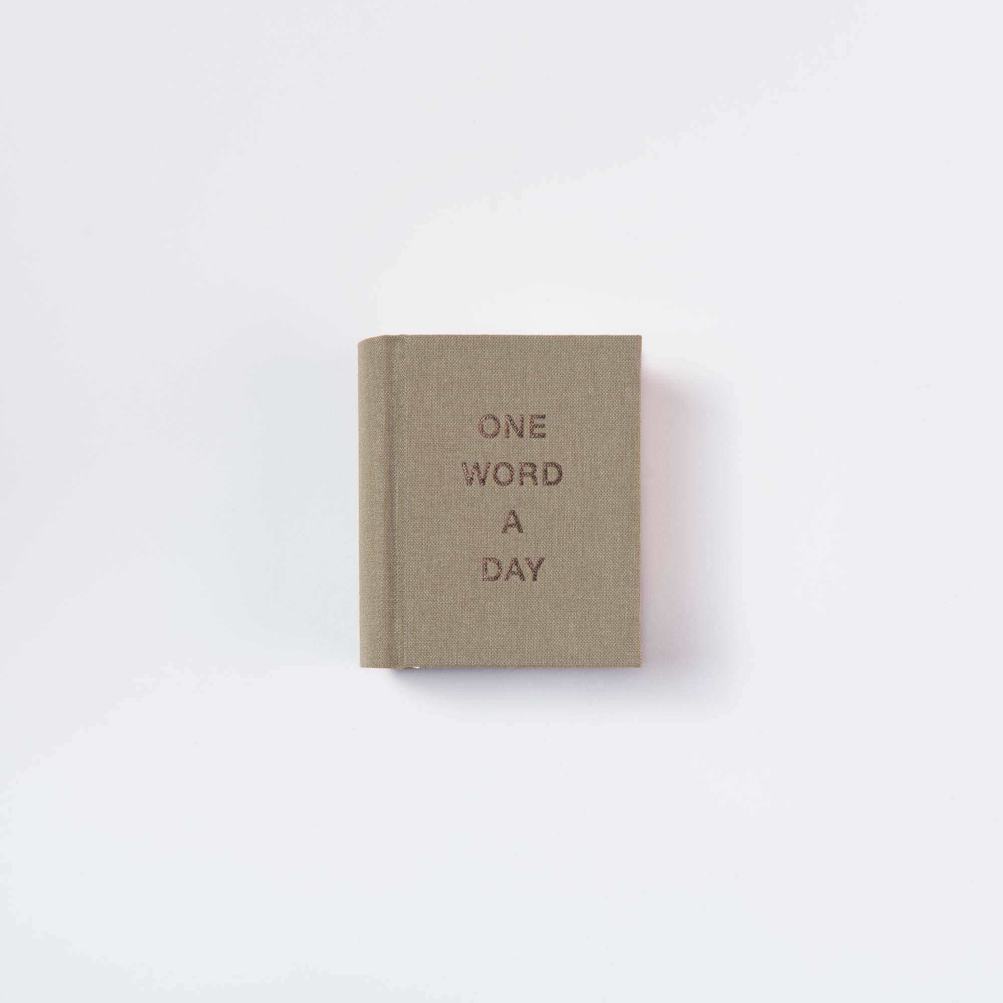 Ein kompaktes, braunes OWAD Elements Mini-Tagebuch von paperlux mit "ONE WORD A DAY" in Fettdruck auf dem Einband und einem schlichten weißen Hintergrund - ideal als liebevolles Geschenk.