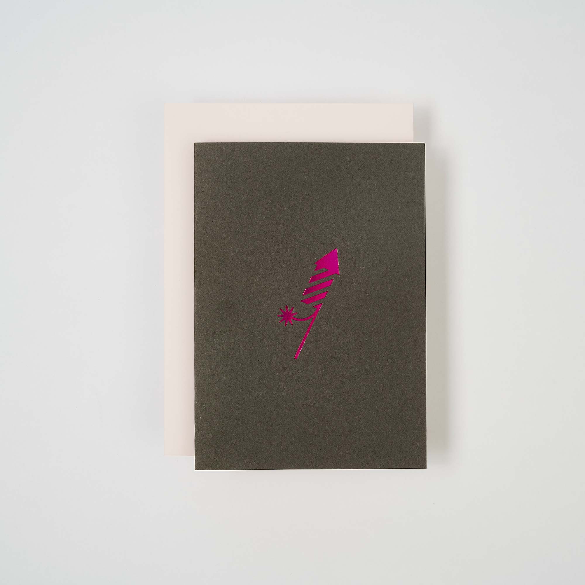 Die Karte Feuerwerk von paperlux.store präsentiert ein festliches dunkelgrünes Design mit einer rosa Rakete auf dem Cover, elegant auf weißem Grund. Diese farbenfrohe Karte eignet sich perfekt für einen Neujahrsgruß.