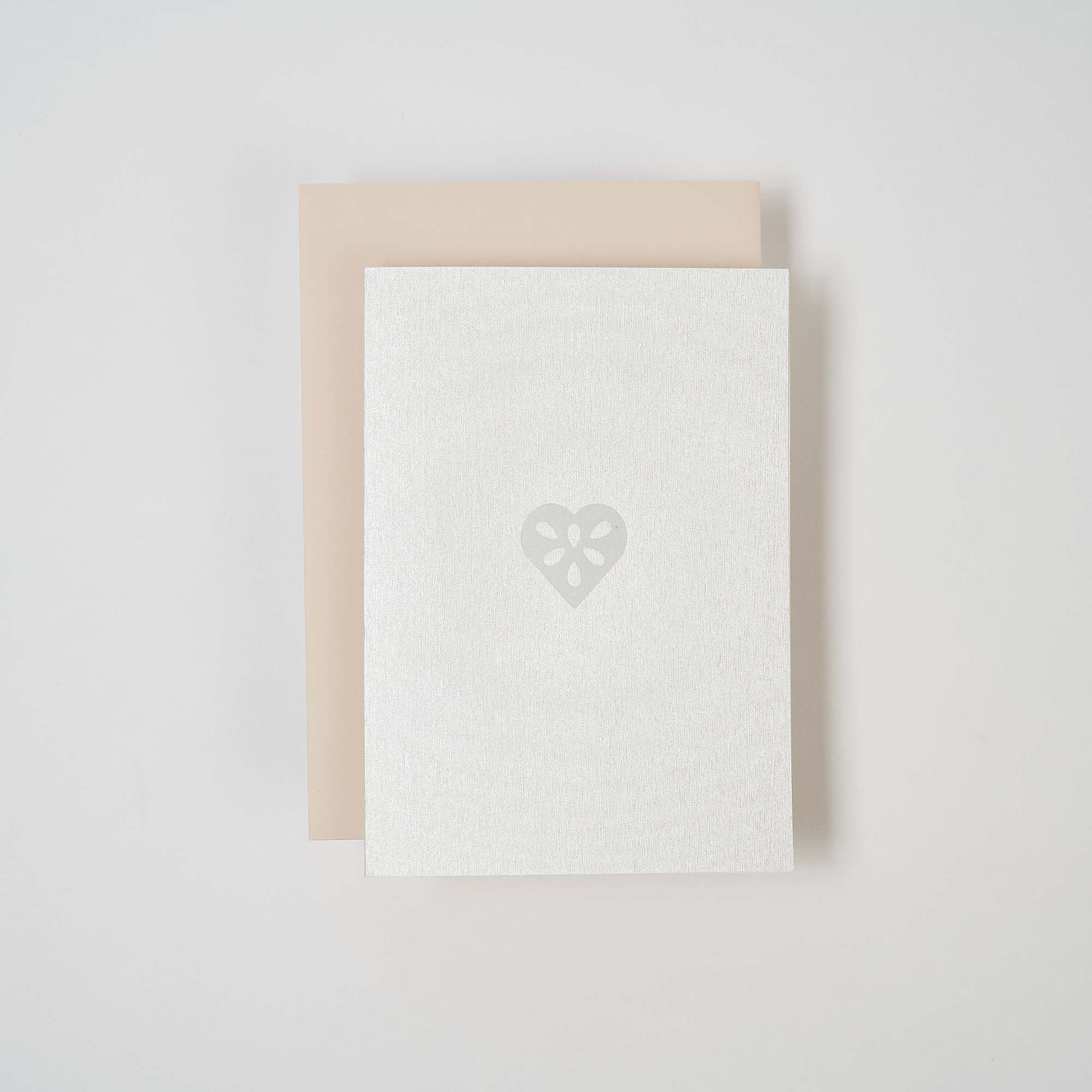 Zwei gestapelte Karten auf weißem Hintergrund: Die obere Karte ist die paperlux.store Weihnachtskarte Lebkuchenherz mit einem dezenten Herzmotiv in der Mitte, die untere Karte ist hellbeige.