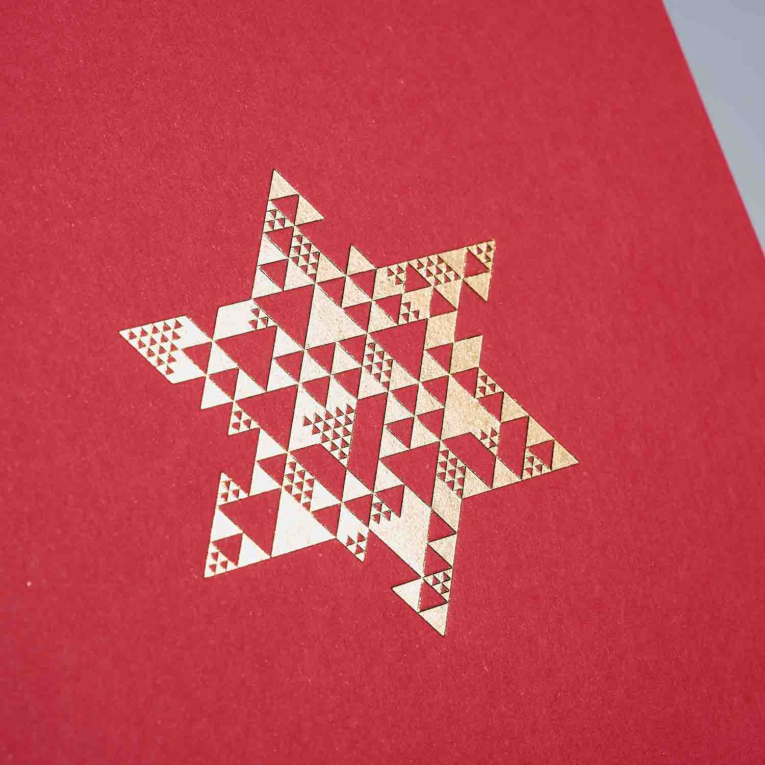 Das Weihnachtskarten 2er-Set Snow & Coral von paperlux.store zeigt einen goldenen geometrischen Stern aus kleinen Dreiecken auf rotem Hintergrund und bietet eine festliche und moderne A6 Klappkarte für Ihre Weihnachtskartenkollektion.