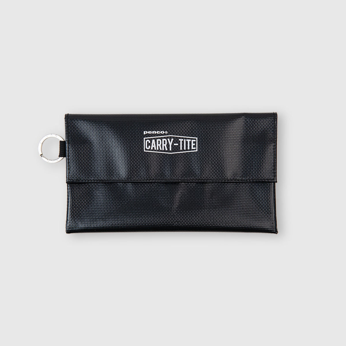Ein schwarzes, rechteckiges „Penco Carry Tite Tarp“-Stifttäschchen aus PVC-Planenstoff, mit einem silbernen Schlüsselring auf der linken Seite und dem weißen Aufdruck „CARRY-TITE“ auf der Vorderseite, fotografiert vor einem hellgrauen Hintergrund. Dieses Etui von Penco vereint Stil und Funktionalität für den täglichen Gebrauch.