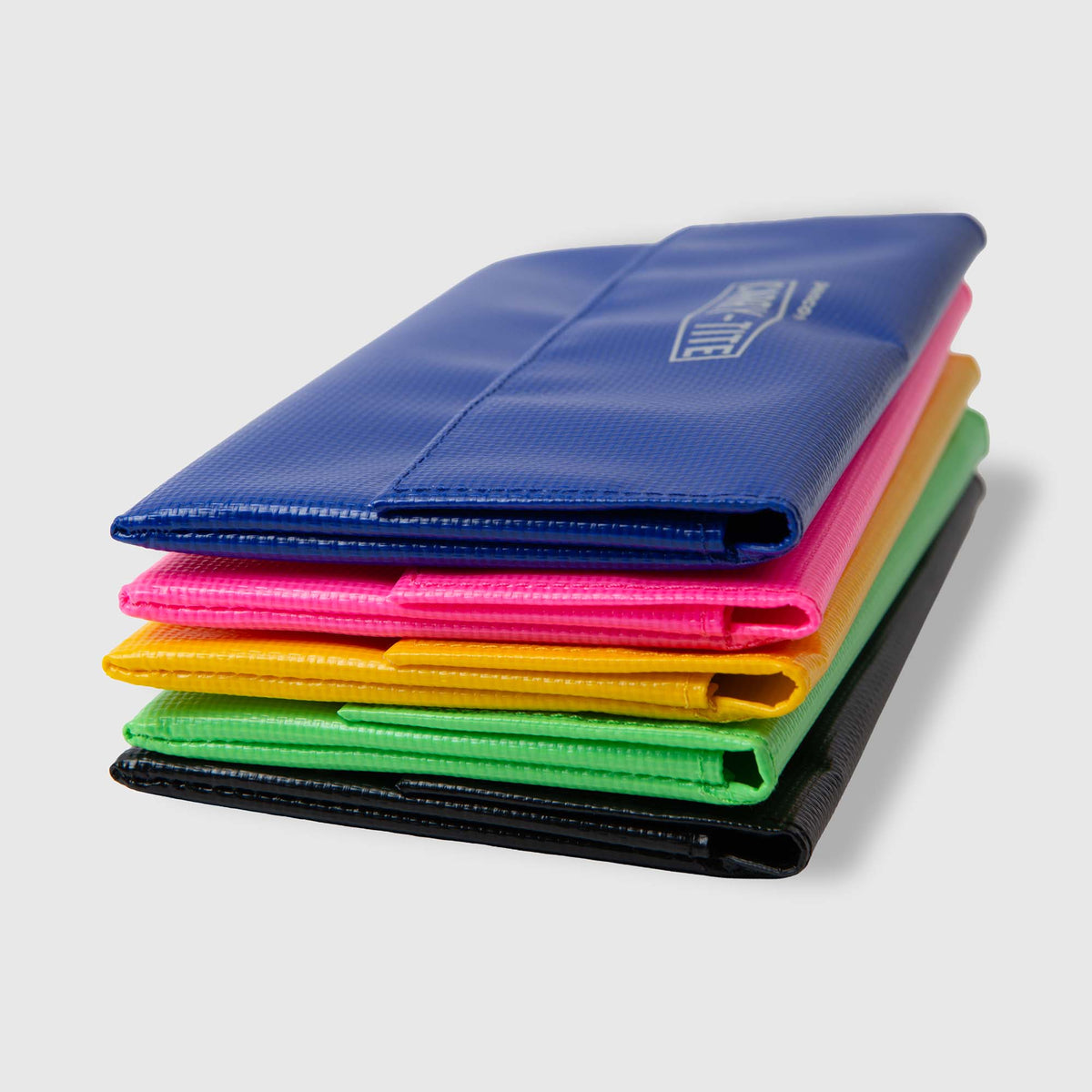 Ein Stapel aus fünf bunten Ordnern – blau, rosa, gelb, grün und schwarz –, der ordentlich auf einem hellgrauen Hintergrund neben einem „Penco Carry Tite Tarp“-Stiftetui angeordnet ist, verleiht Ihrem Arbeitsplatz eine farbenfrohe und zugleich praktische Note.