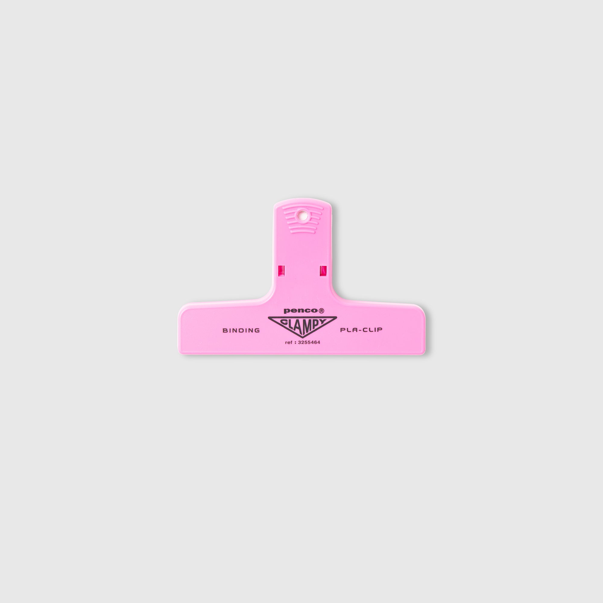 Ein rosa Penco Clampy PlaClip Kunststoff mit einer Öse zum Aufhängen, auf dem die Aufschriften „BINDING“ und „PLR-CLIP“ sowie der Markenname „Penco“ in Schwarz aufgedruckt sind, erinnert an das klassische Design des japanischen Clampy-Clips und wird vor einem schlichten hellgrauen Hintergrund dargestellt.