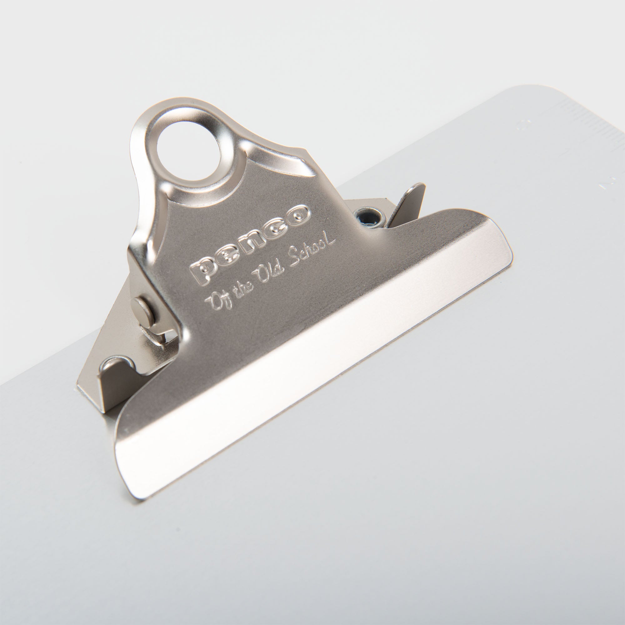 Nahaufnahme eines Penco Clipboards - A4 Aluminium-Clips, der an einer weißen Tafel befestigt ist, mit eingraviertem "Penco" auf dem Clip.