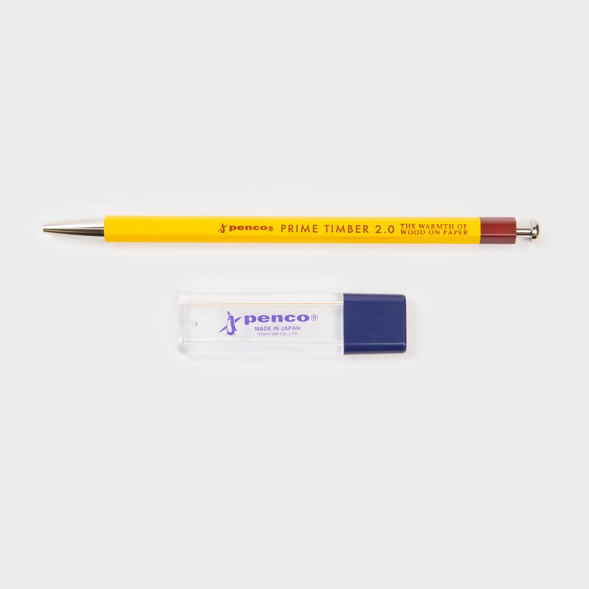 Ein gelber Penco Prime Timber Druckbleistift (2 mm) ruht über einem klaren und einem blauen Penco-Radiergummi, die beide ein elegantes japanisches Design auf einem schlichten weißen Hintergrund aufweisen.