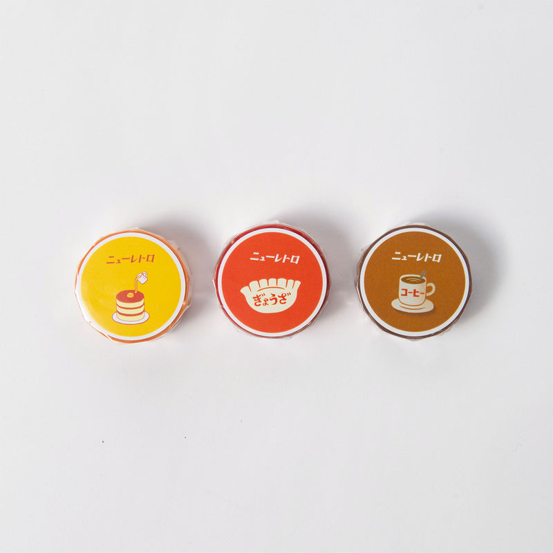 Drei runde, bunte Klebeband-Dosen von Hightide sind nebeneinander auf weißem Hintergrund angeordnet. Jede Dose zeigt ein einzigartiges Design: Pfannkuchen auf Gelb, Toast auf Rot und eine Kaffeetasse auf Braun. Über den Illustrationen steht ein japanischer Text, der für zusätzlichen Spaß sorgt.