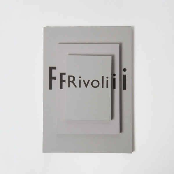 Der Skizzen- und Schreibblock Rivoli hellgrau von Carta Pura verfügt über ein minimalistisches Design mit dem Wort „Rivolii“ in Schwarz, abgeschirmt durch drei überlappende graue Rechtecke auf einem glatten, briefpapierähnlichen grauen Hintergrund.