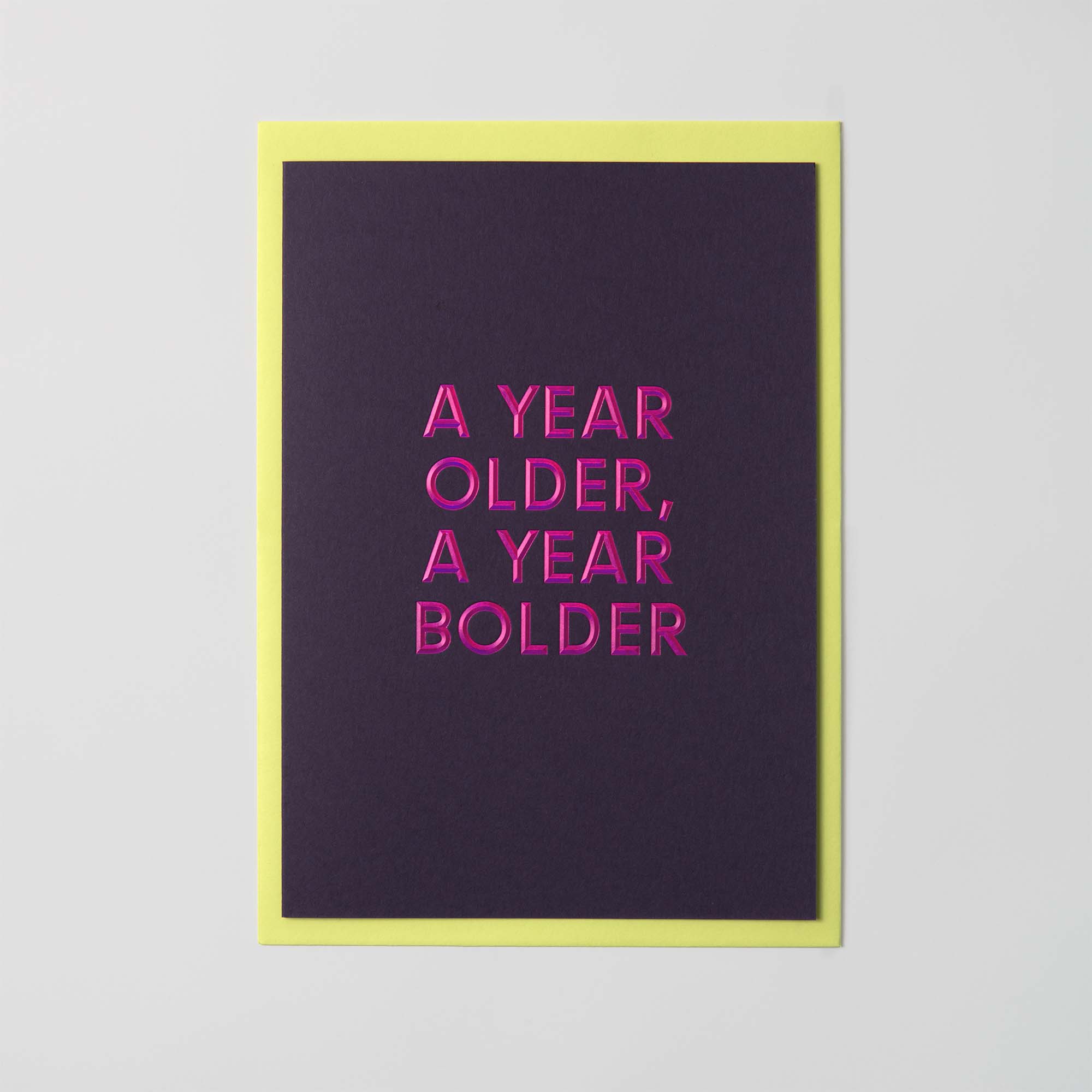 Die Geburtstagskarte „AYOAYB“ von paperlux.store verfügt über einen dunklen Hintergrund, einen hellen Rand, den kräftigen, leuchtend rosa Text „A YEAR OLDER, A YEAR BOLDER“ und eine auffällige Heißfolienprägung.
