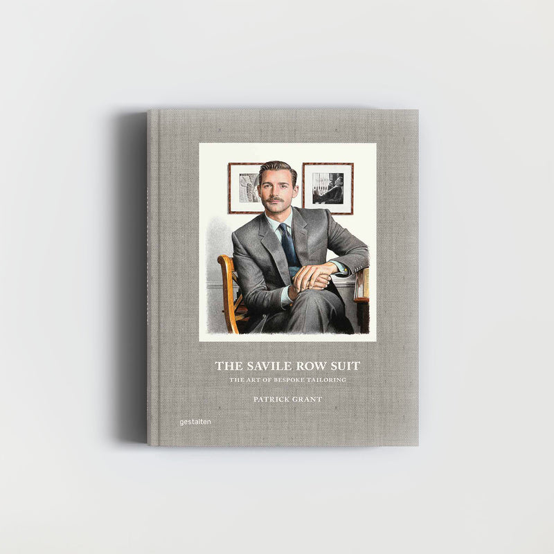 Das Buch „The Savile Row Suit“ vom Gestalten Verlag zeigt auf dem Cover einen Mann im Anzug in einem Stuhl vor einem grauen Hintergrund mit gerahmten Fotos, der die Essenz maßgeschneiderter Schneiderkunst einfängt.