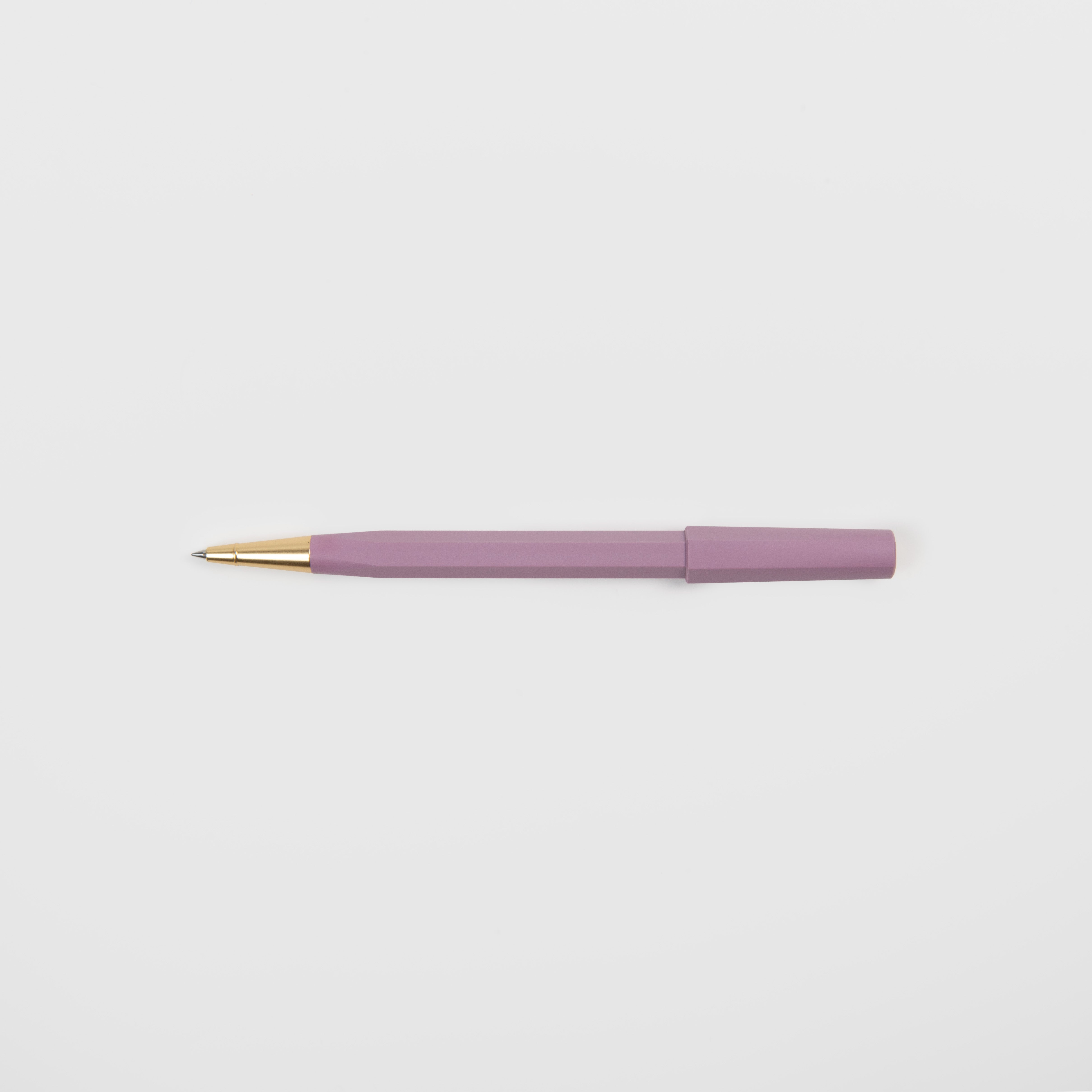 Ein Ystudio Rollerball - Ocean Edition Kugelschreiber mit violettem Gehäuse und goldener Spitze aus recycelten Fischernetzen liegt waagerecht auf einem schlichten weißen Hintergrund.