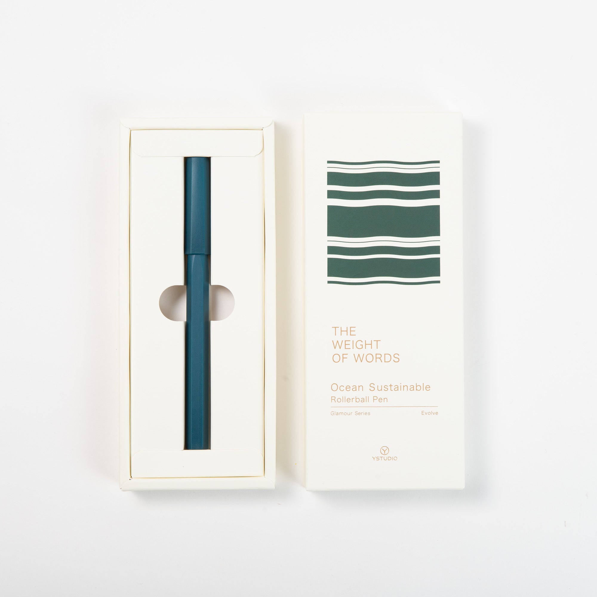 Ein tealfarbener Ystudio Rollerball - Ocean Edition in einer weißen Schachtel mit grünem Wellenmuster. Auf dem Deckel steht "THE WEIGHT OF WORDS Ocean Sustainable Rollerball Pen" und der Hinweis, dass er aus recycelten Fischernetzen hergestellt wurde.