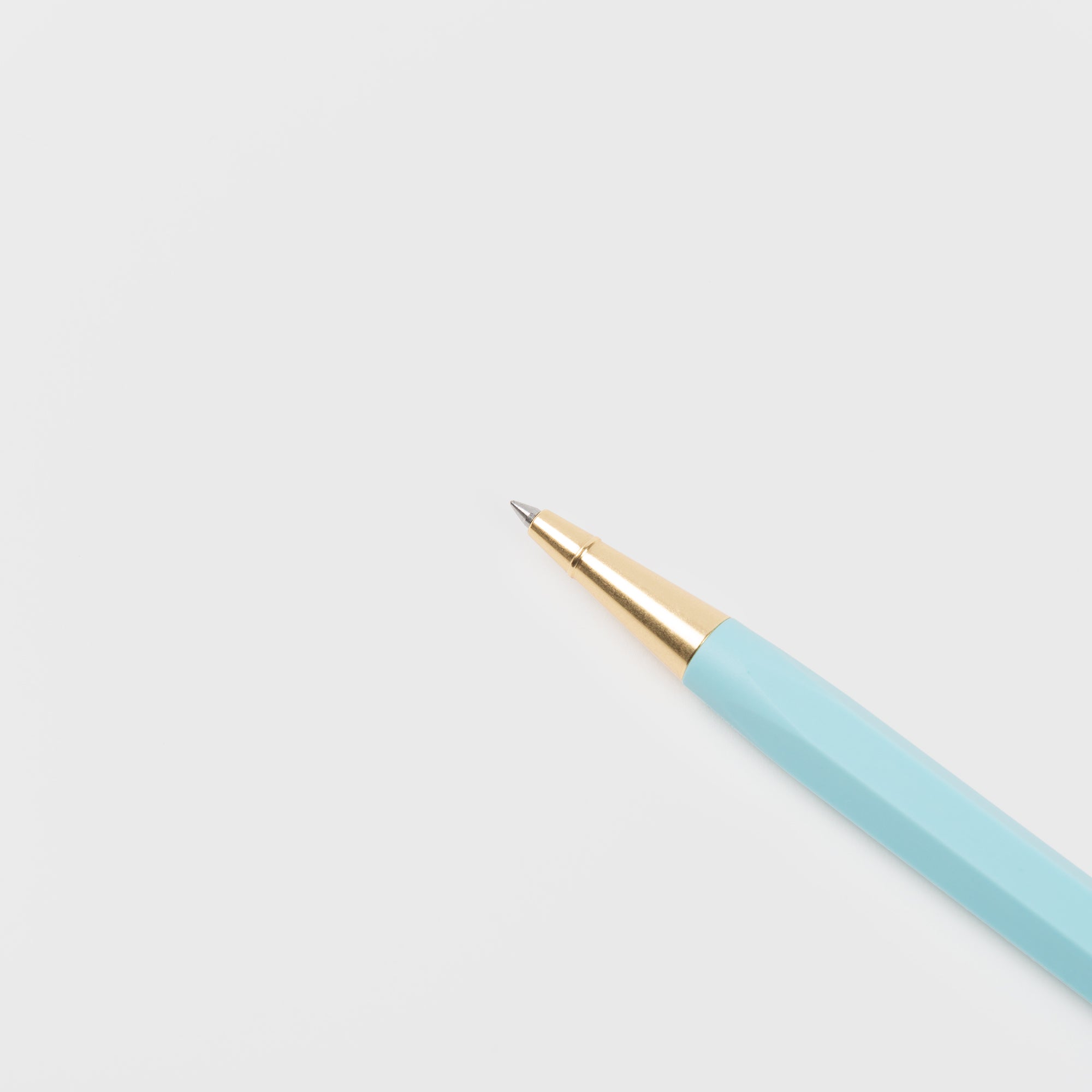 Ein Ystudio Rollerball - Ocean Edition Stift liegt schräg auf einer leeren weißen Fläche, die Spitze ist in die linke obere Ecke gerichtet.